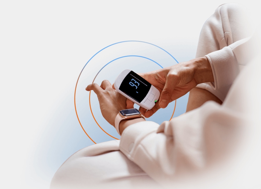 A close up view of a person holding a digital heart monitor and synching it with their Apple watch.
